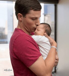 A photograph of a father holding his newborn baby 